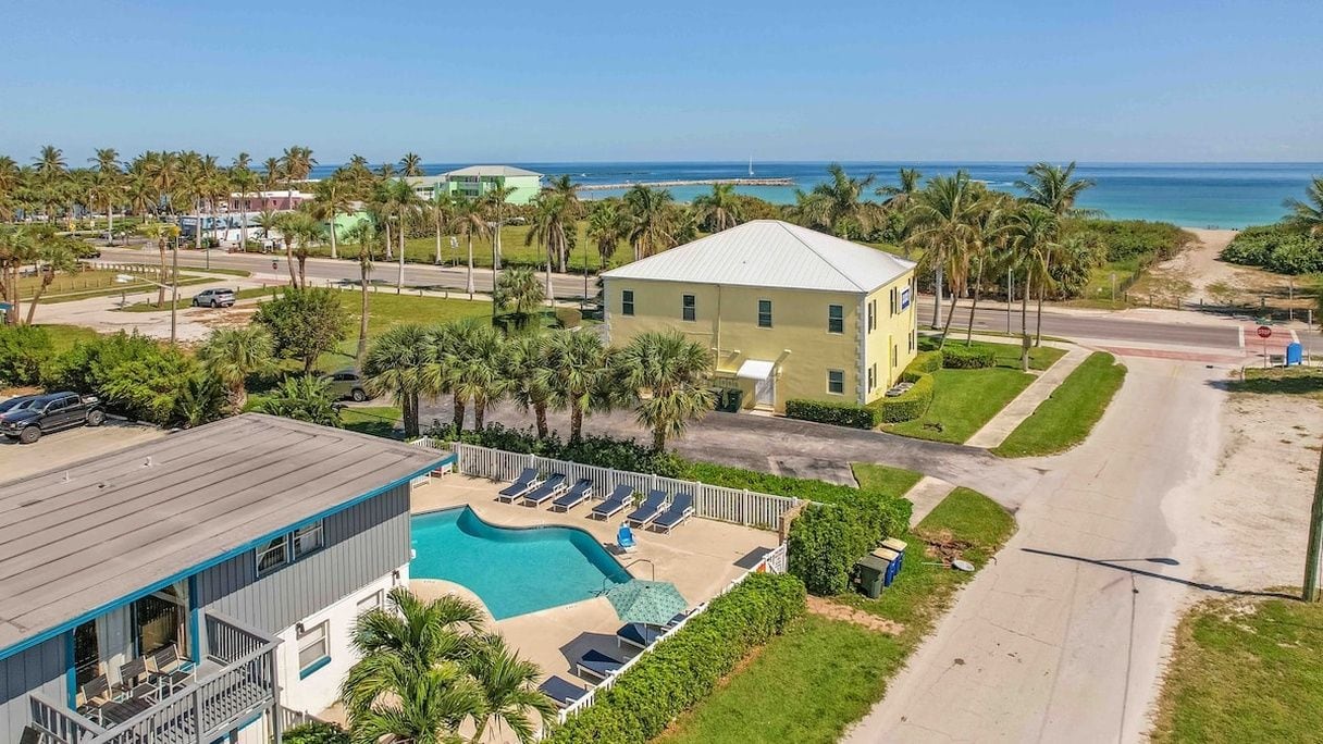 A hotel with a swimming pool, a beach view, and a parking area.