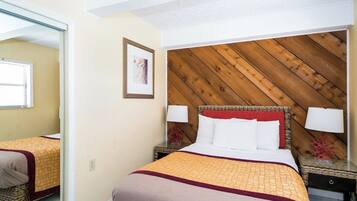 A hotel room with a bed, bedside tables, a mirror, and a wooden headboard.