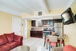 A compact living space with a kitchenette, a sofa, a dining table with chairs, and a television mounted on the wall. - 2/1 Hutchinson Island, Pool, WIFI, Sleep 6, B (Fort Pierce)