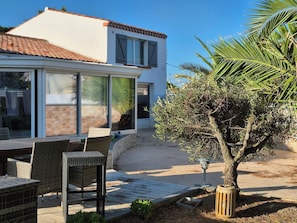 Een modern huis met een terras, tuinmeubilair en een kleine boom.