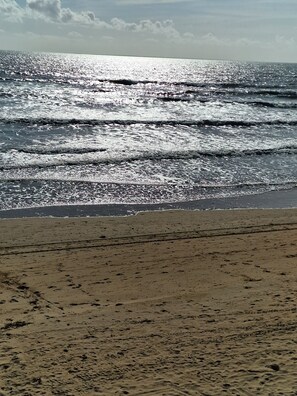 Een strand met golven en een heldere lucht.