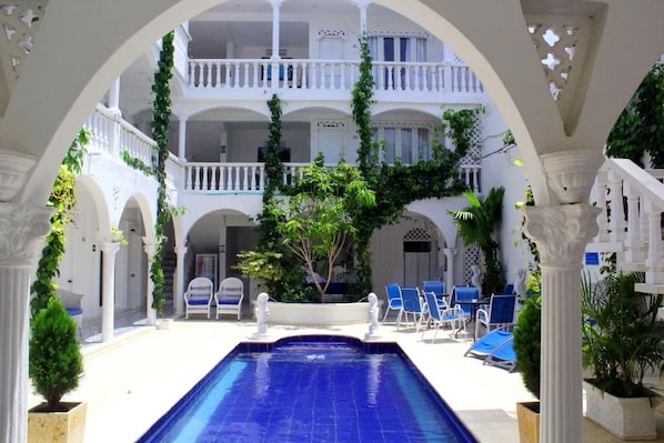 A pool area with a blue pool, white columns, and blue lounge chairs. - Hotel Casa Mara by Akel Hotels (Cartagena de Indias)