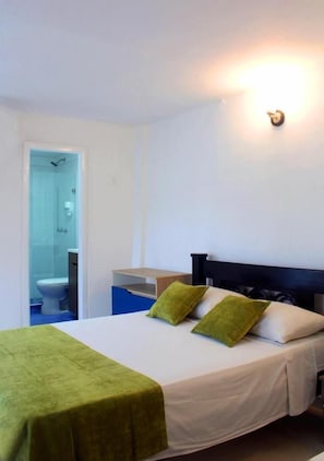 A hotel room with a bed, a nightstand, a wall-mounted light, and a bathroom visible through an open door. - Hotel Casa Mara by Akel Hotels (Cartagena de Indias)
