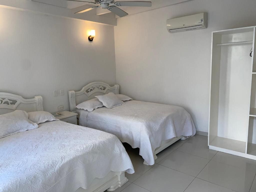Un dormitorio con dos camas, ventilador de techo, aire acondicionado y armario.