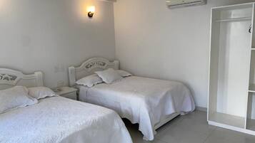 Un dormitorio con dos camas, ventilador de techo, aire acondicionado y armario.