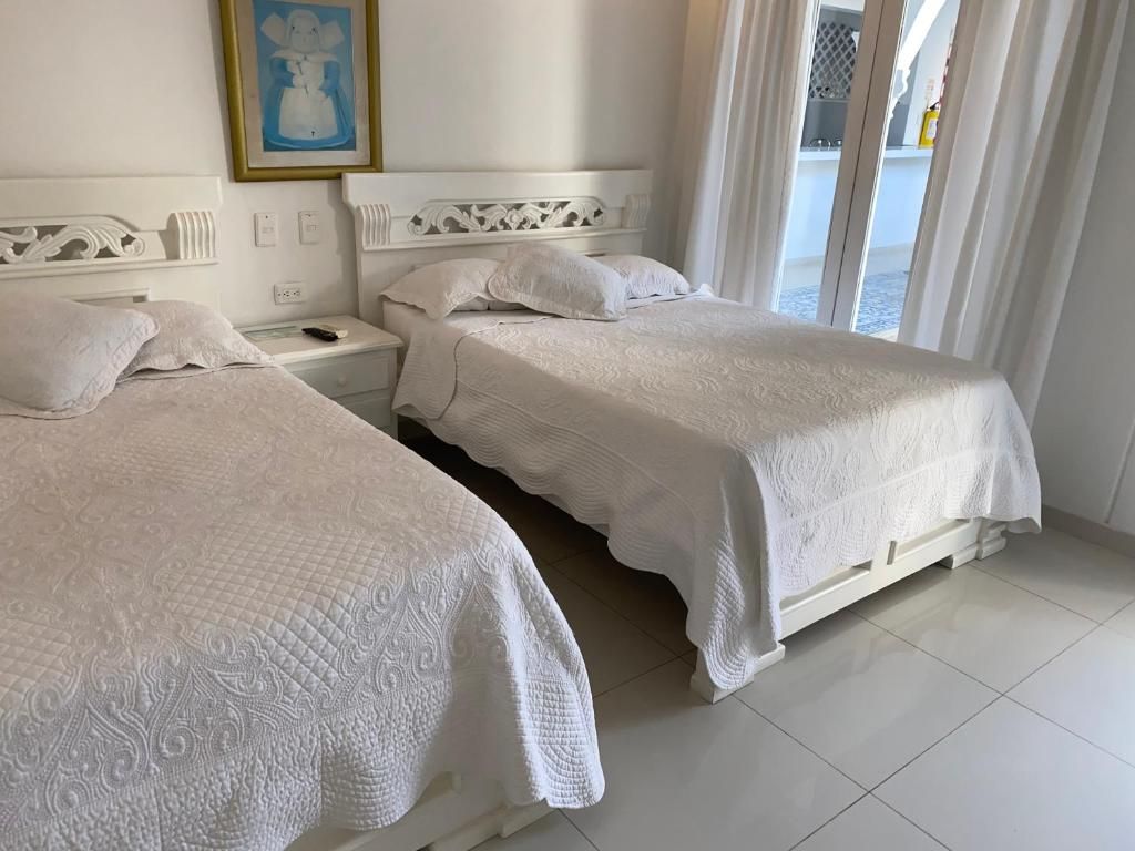 Habitación de hotel con dos camas, una mesita de noche, un cuadro en la pared y vistas al exterior.