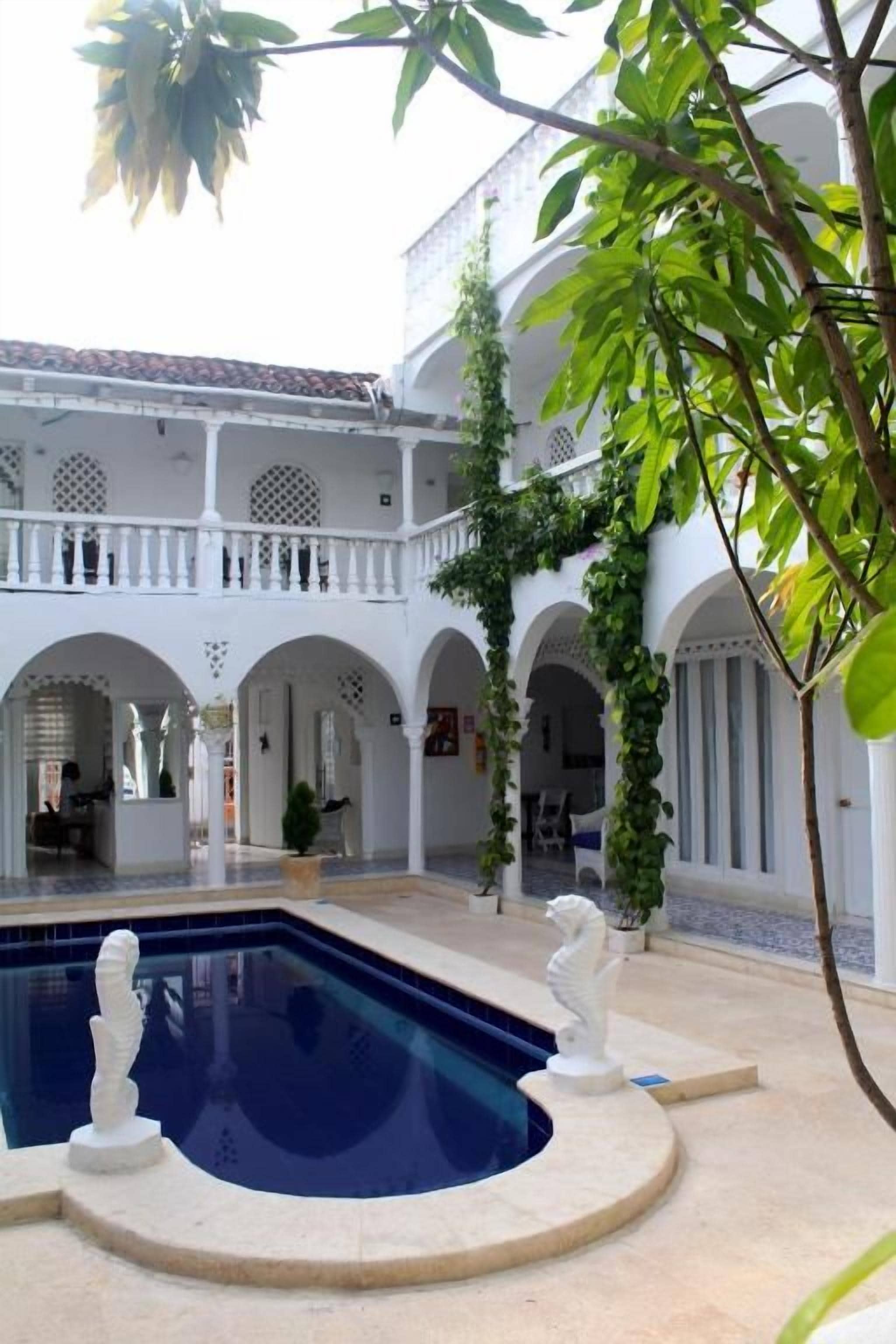 A courtyard with a swimming pool, white columns, and a building with balconies.