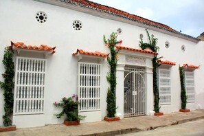A white building with red-tiled roofs, barred windows, and a gated entrance. - Hotel Casa Mara by Akel Hotels (Cartagena)
