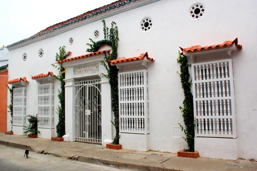 Un bâtiment blanc avec un toit en tuiles, des fenêtres grillagées et une enseigne sur laquelle on peut lire « Casa de la Cultura ».