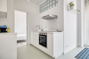 A modern kitchen with white cabinetry, a built-in oven, and a stainless steel range hood. - Hostmate- Milano-Minimal Nest (Milan)