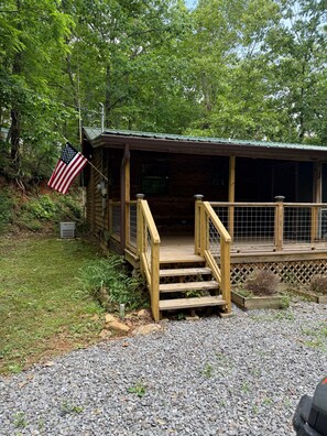 A wooden cabin with a porch, a wooden staircase, and an American flag. - Cozy Mountain Cabin Retreat in Murphy, NC (Murphy)
