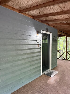 A covered porch with a wooden ceiling, a green door, and a welcome mat. - Cozy Mountain Cabin Retreat in Murphy, NC (Murphy)