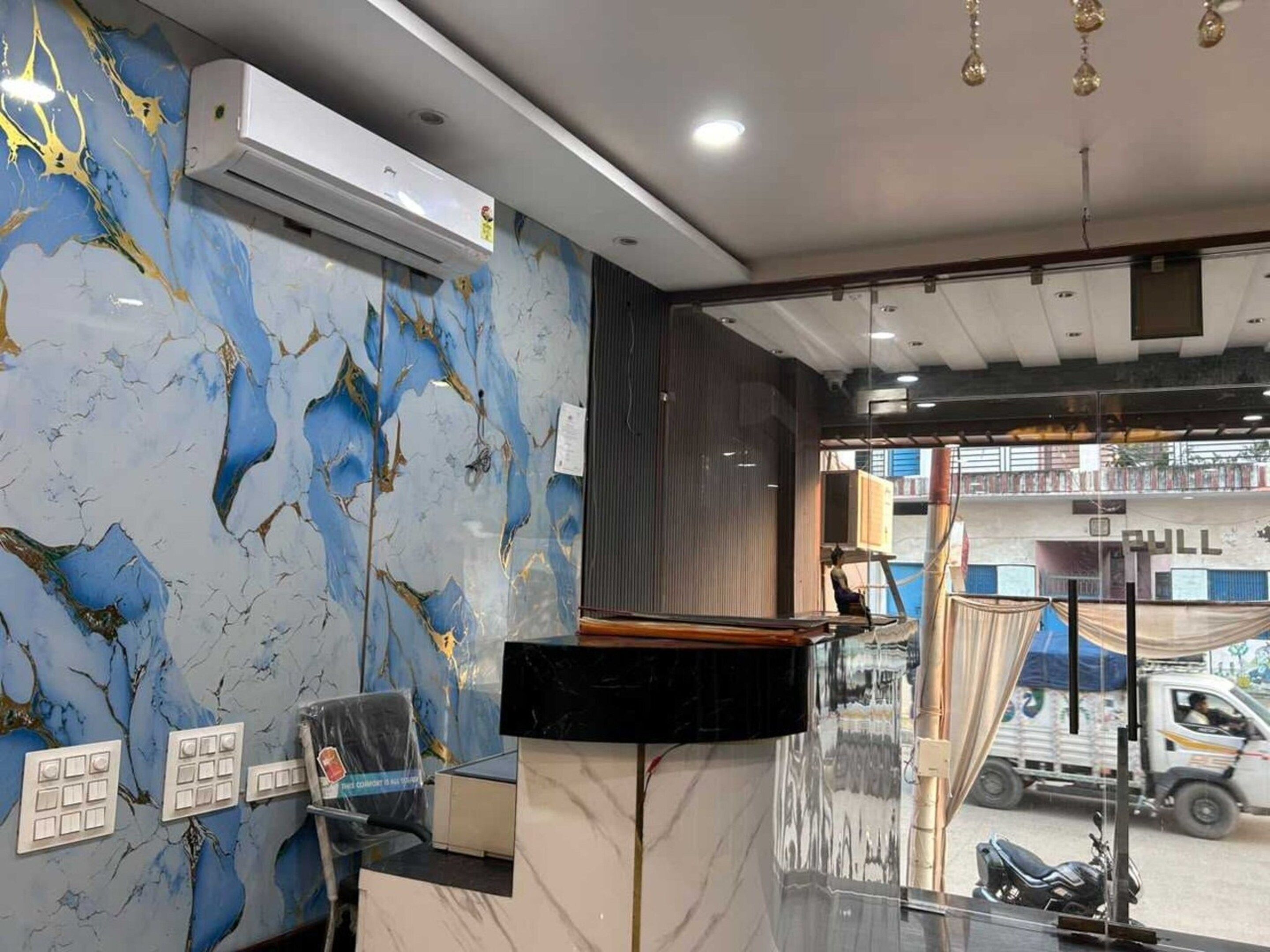 Et hotellets reception med marmorvægge, en receptionsdisk og udsigt til gaden.