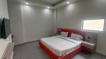 Habitació d'hotel amb un llit, una taula de nit, un televisor i una finestra.