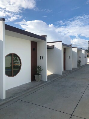 A row of modern, numbered hotel rooms with a clean design and a view of the sky. - Feel at home resort  (Nakhon Pathom)