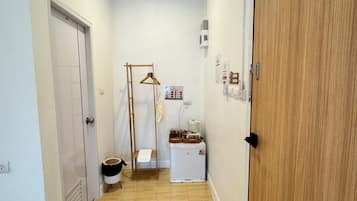 A narrow hallway with a wooden door on the right, a white wall, and a small white appliance on the left.