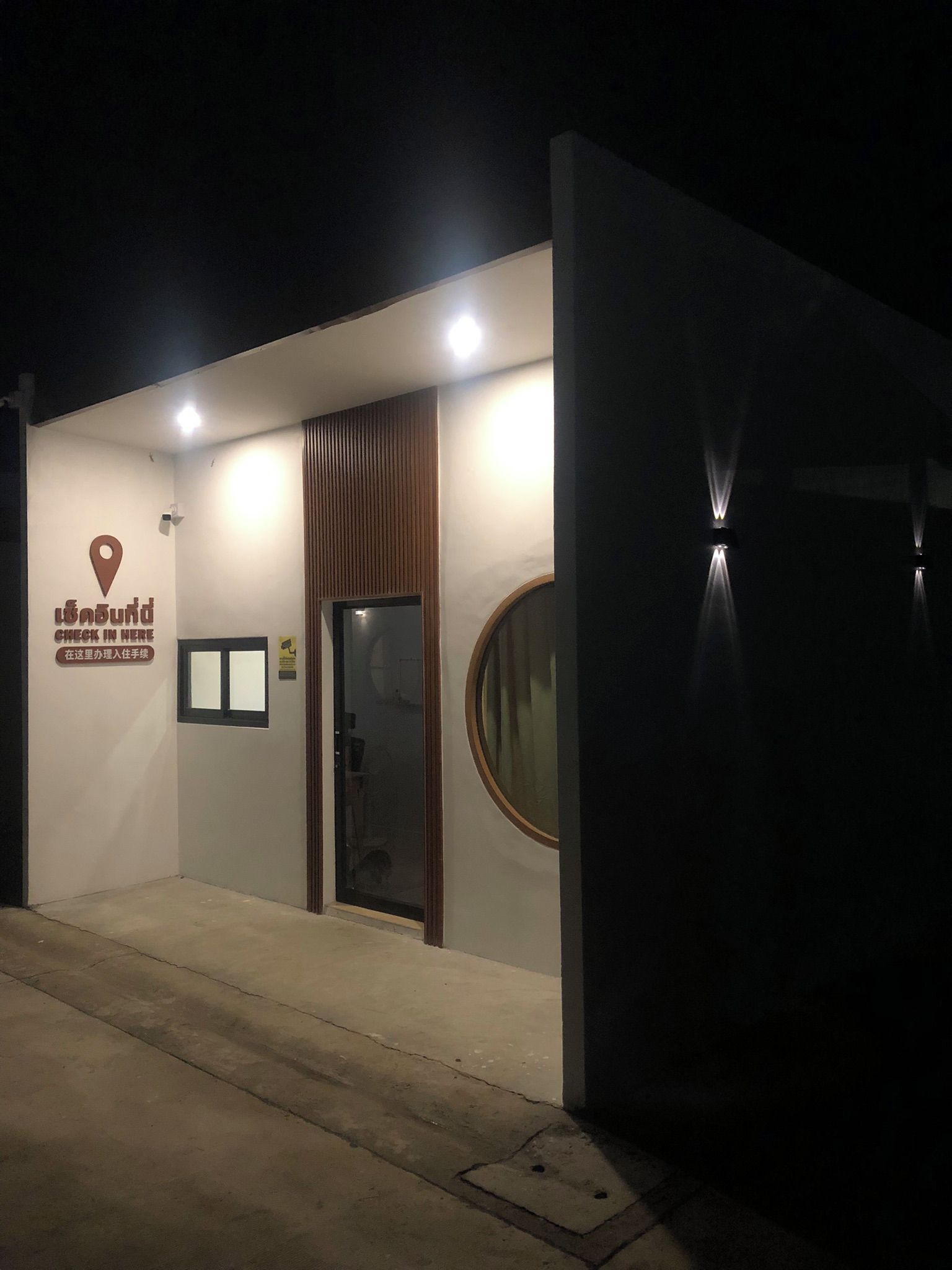 A building entrance with a sign indicating a check-in area, a door, and a circular window.