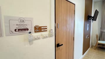 A hallway with a wooden door, a wall-mounted Wi-Fi sign, a telephone, and a power outlet.