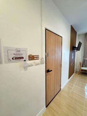 Un pasillo con una puerta de madera, un letrero de Wi-Fi en la pared, un teléfono y un enchufe.