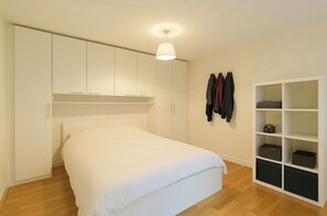 Een slaapkamer met een bed, een kledingkast en een boekenkast.