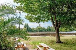 A park with picnic tables, benches, and a large tree. - Tranquil 1-bedroom apartment in the heart of London right next to the riverside (London)