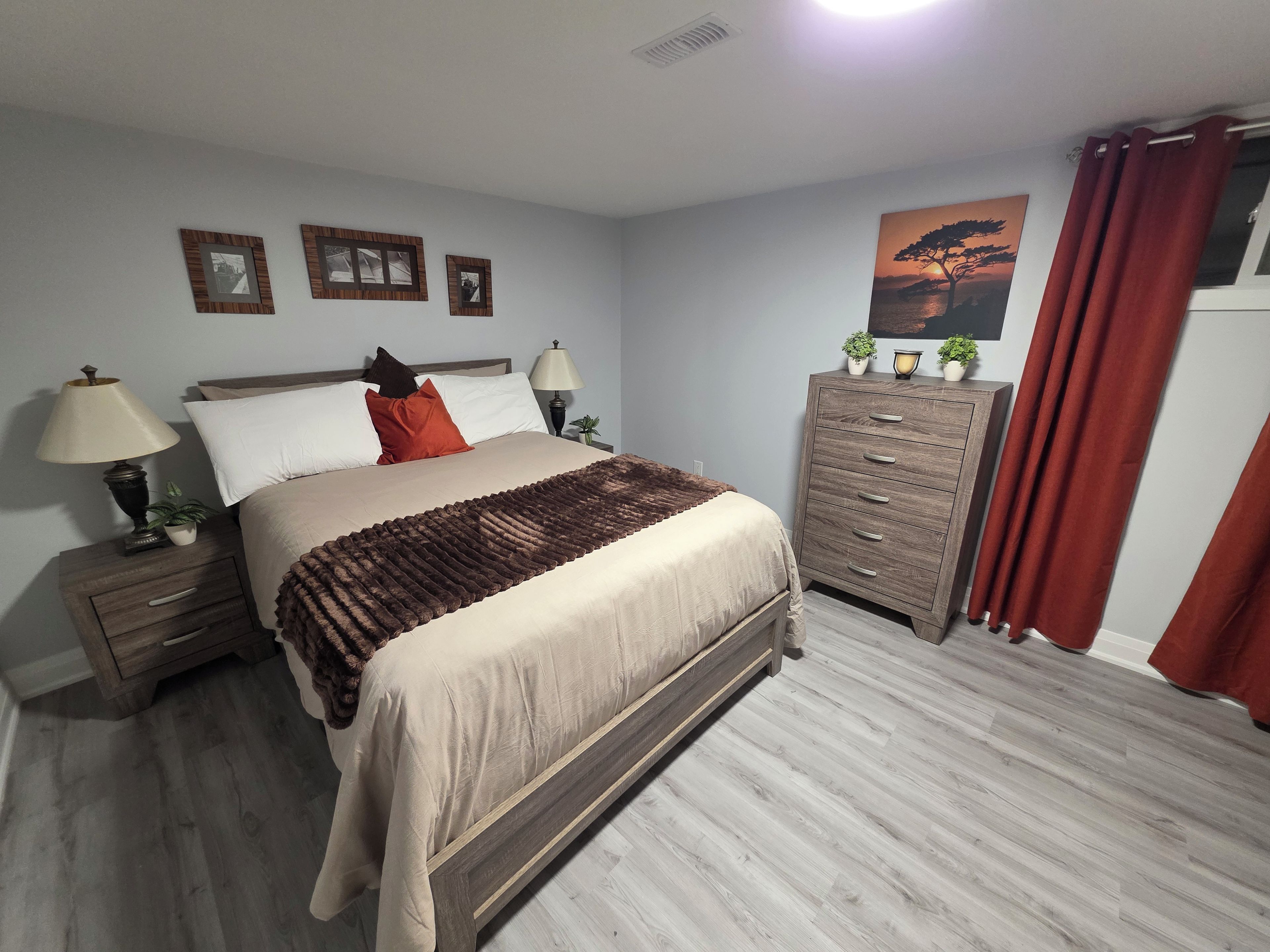 Une chambre à coucher avec un lit, des tables de chevet, une commode et un tableau au mur.