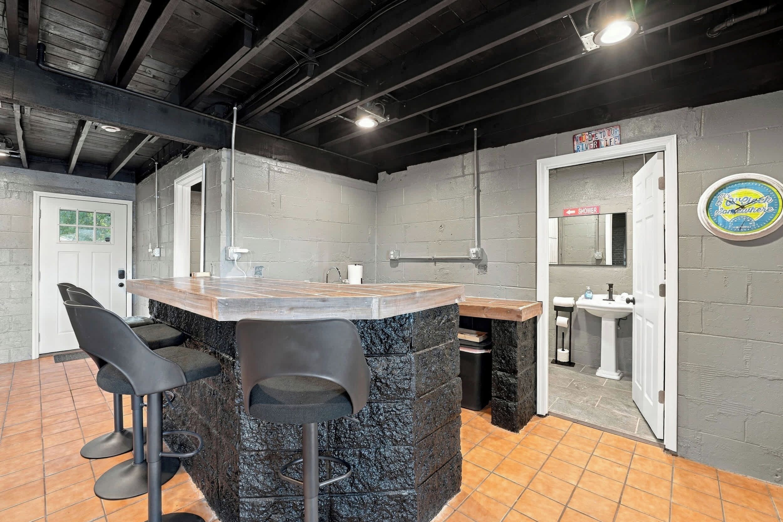 Zona de bar con mostrador de mármol, taburetes negros y señal de ducha.