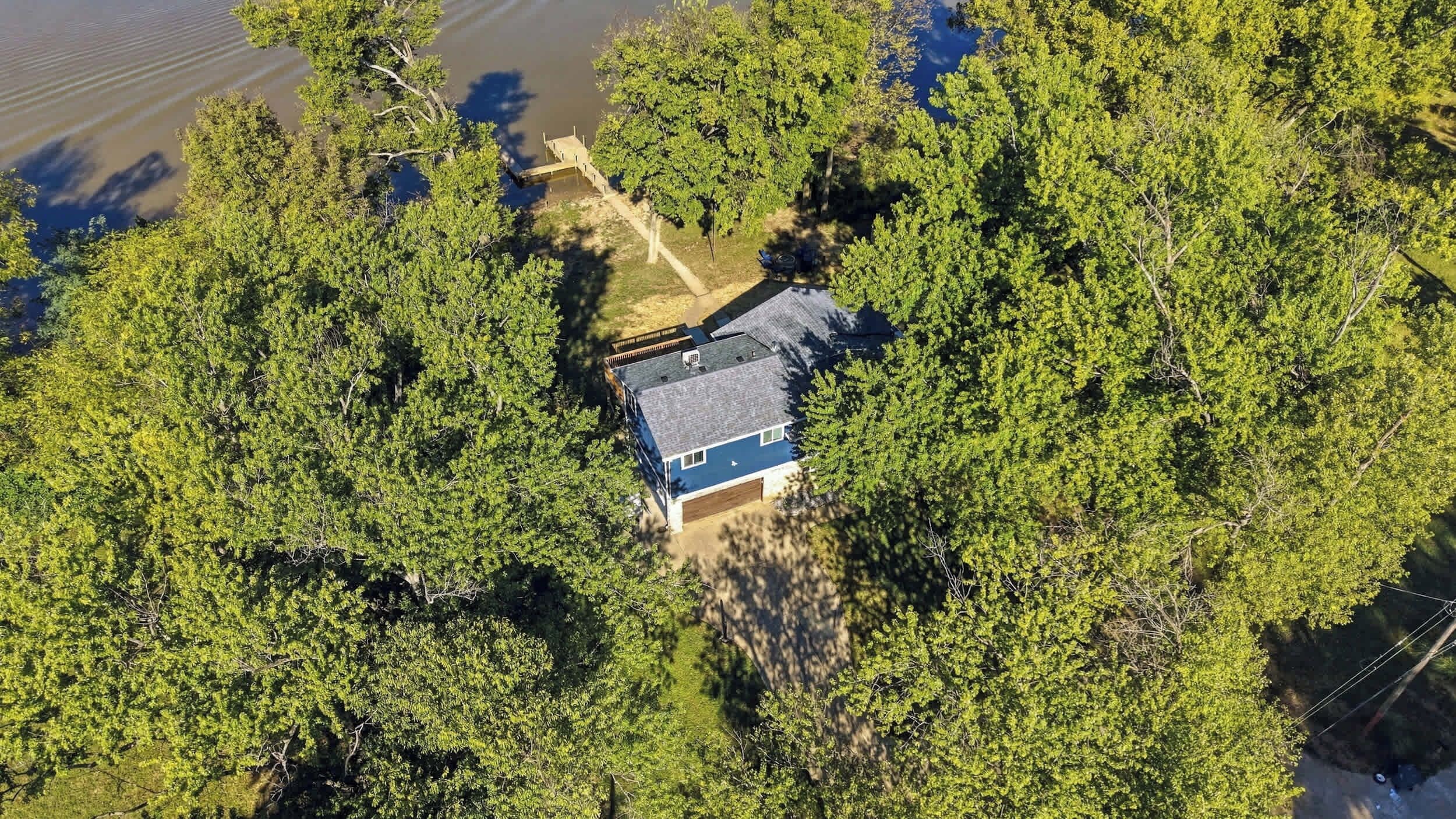 Una casa rodeada de árboles frondosos, con un cielo despejado.