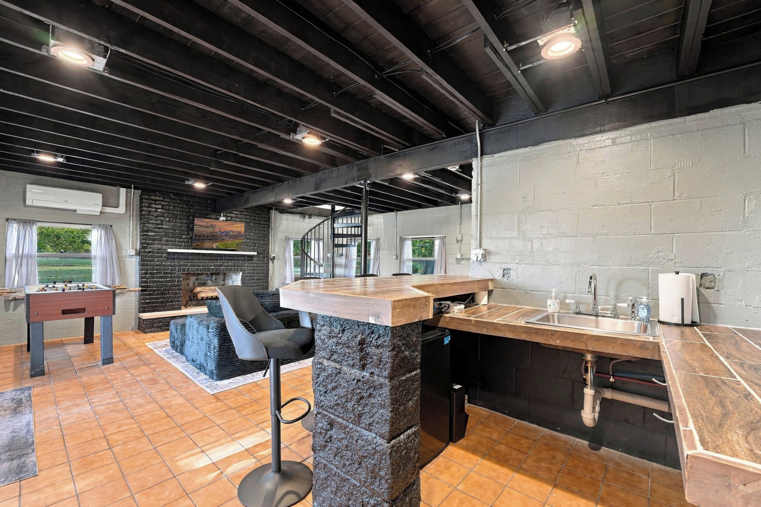 A modern kitchen with a bar area, a foosball table, and a fireplace.