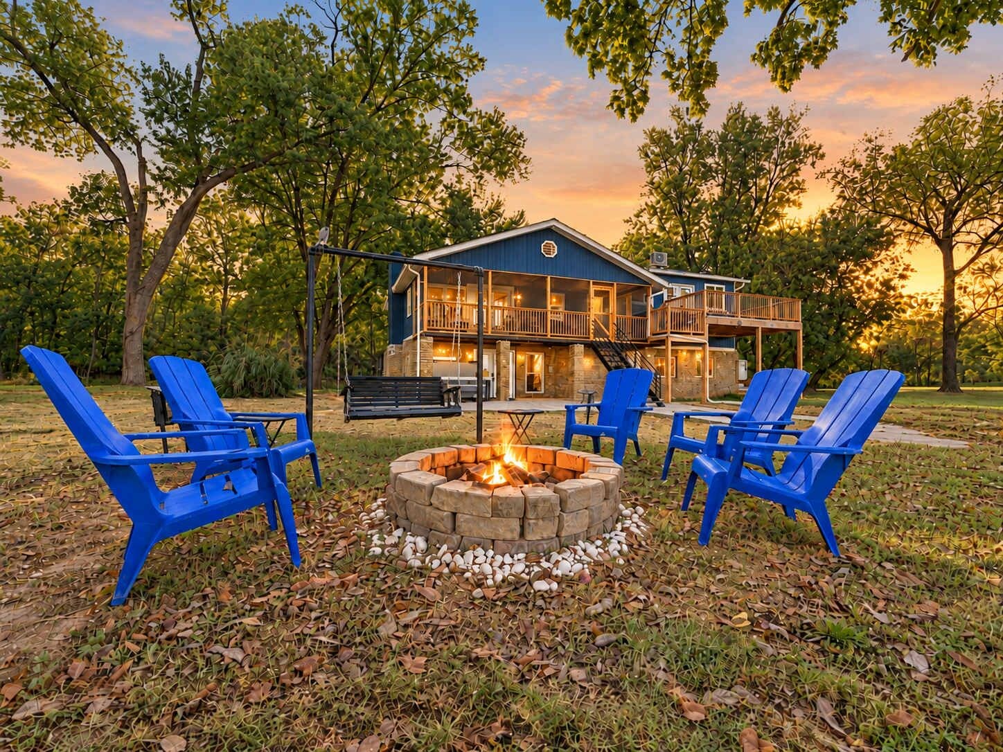 A house with a fire pit and blue chairs in the yard.