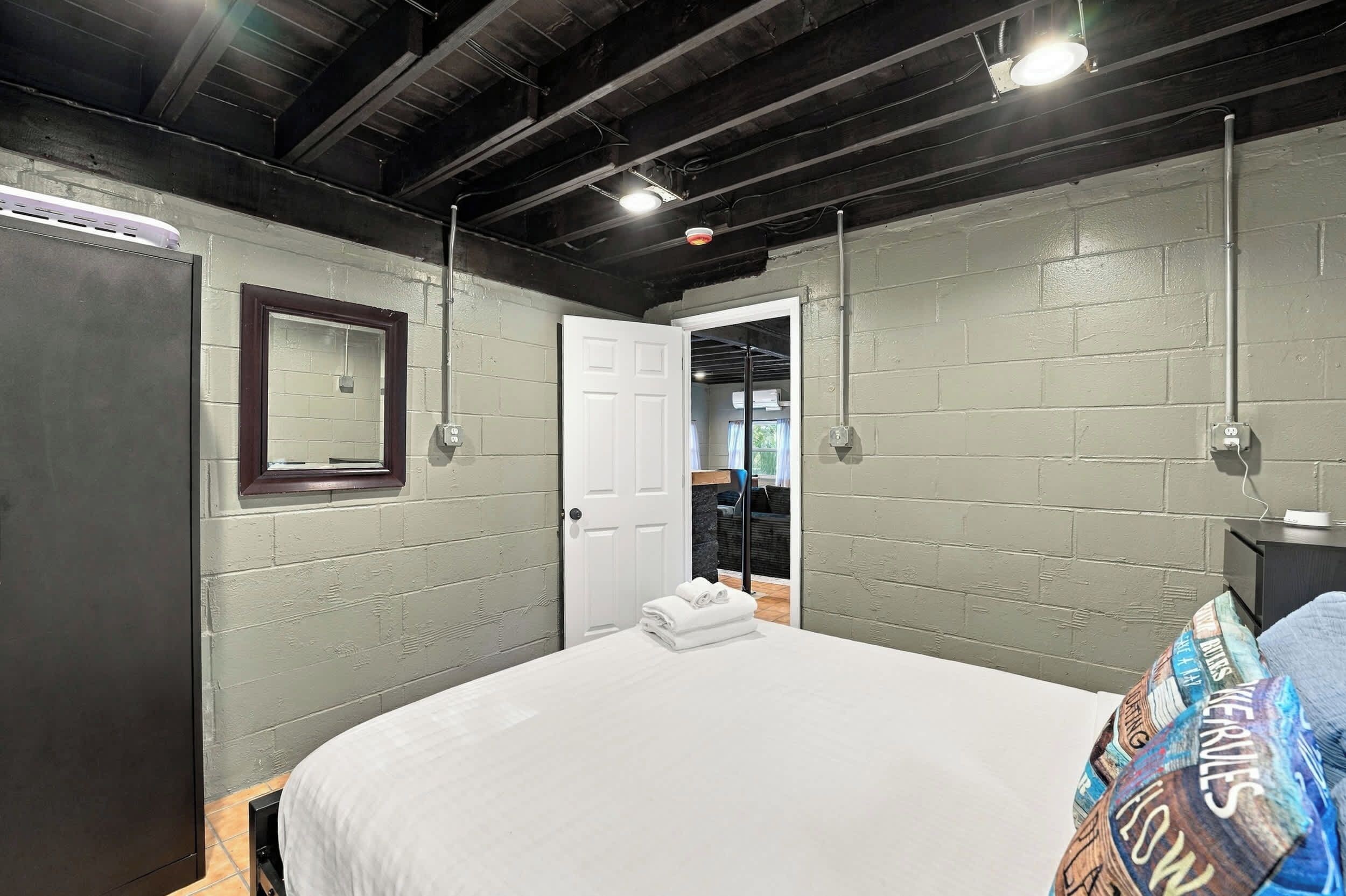 A hotel room with a bed, a door, and a wall-mounted light fixture.