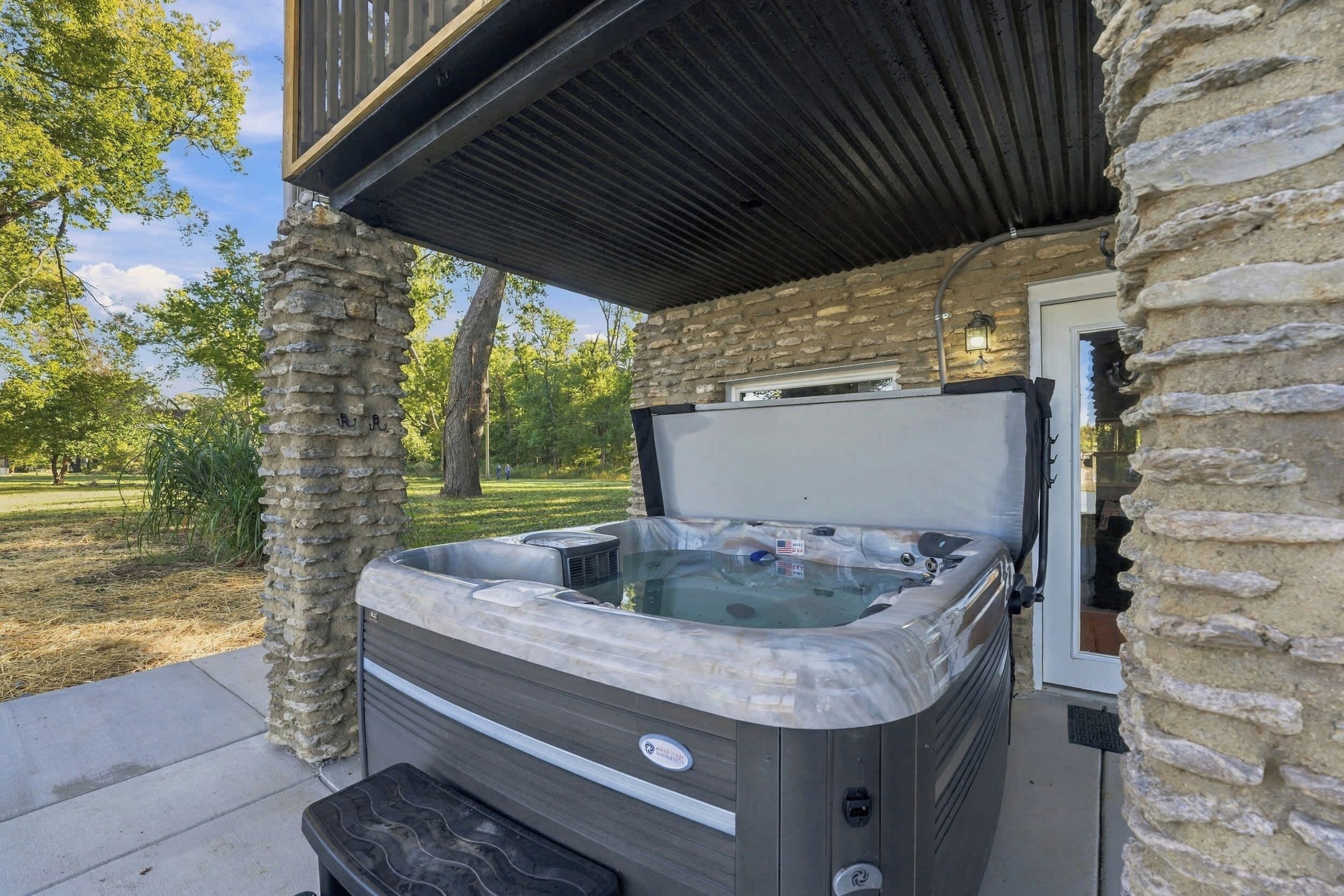 Een hottub met deksel, gelegen voor een stenen muur, buiten.