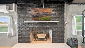 A fireplace with a brick wall, a picture of a race track, and a speaker on the right.