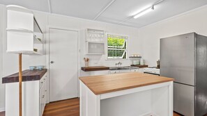 A compact kitchen with white cabinetry, a wooden countertop, and a stainless steel refrigerator. - Coolangatta Dreaming - Pet Friendly Beachside Home - Min. 2 Night Stays (Coolangatta)
