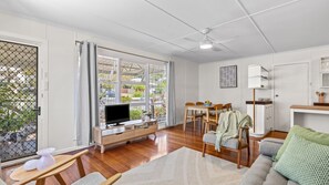 A spacious living area with a television, dining table, and chairs. - Coolangatta Dreaming - Pet Friendly Beachside Home - Min. 2 Night Stays (Coolangatta)