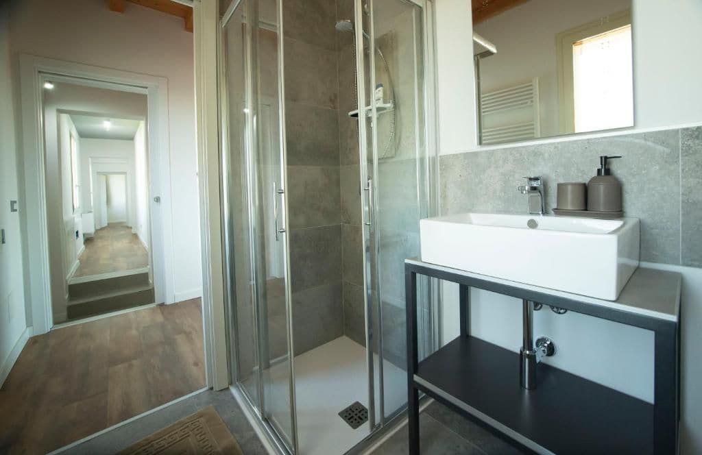 Une salle de bain moderne avec une douche à parois de verre, un lavabo blanc et un miroir au-dessus.