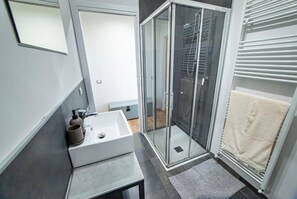 A modern bathroom with a glass shower enclosure, a white sink, and a towel rack. - FORESTERIA LOMBARDA BED AND BIKE CREMONA (Crotta d'Adda)