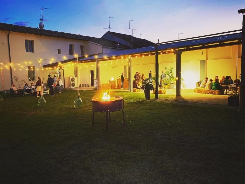 An outdoor gathering area with a fire pit, covered seating, and string lights.