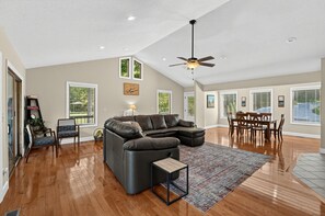 A spacious living room with a sectional sofa, a dining area with a table and chairs, and a ceiling fan. - Hap’s Sweet Hideaway | Lakefront Cabin & Dock (Maynardville)