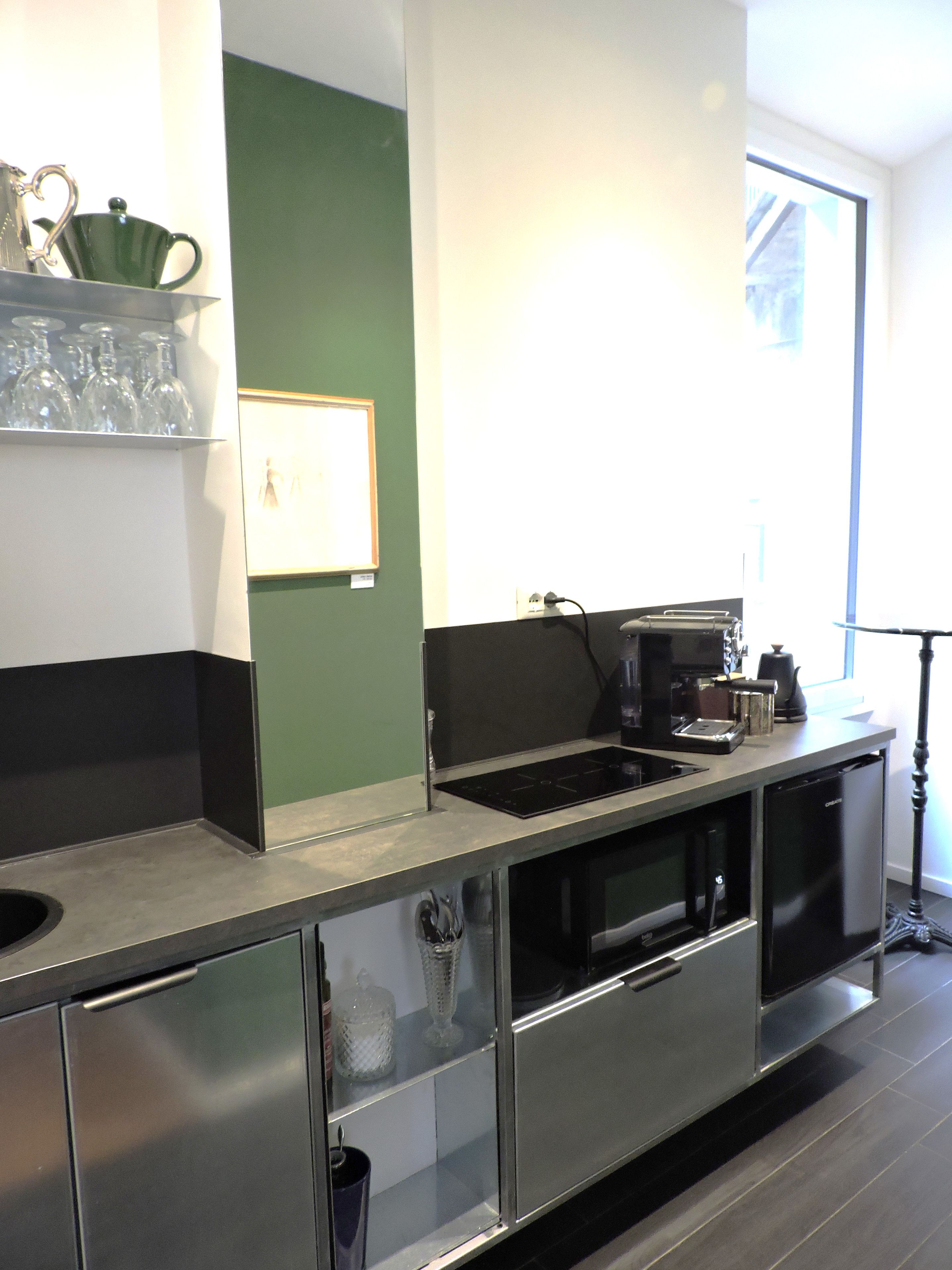 Cozinha moderna com eletrodomésticos de aço inoxidável, máquina de café e vitrine de vidro.