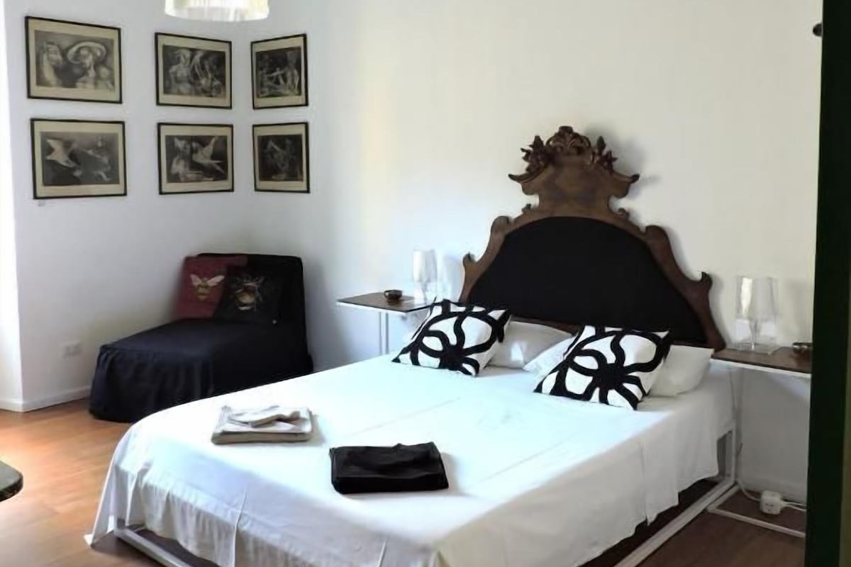 Ein Schlafzimmer mit einem Bett, Nachttischen, einer Hängelampe und gerahmten Bildern an der Wand.