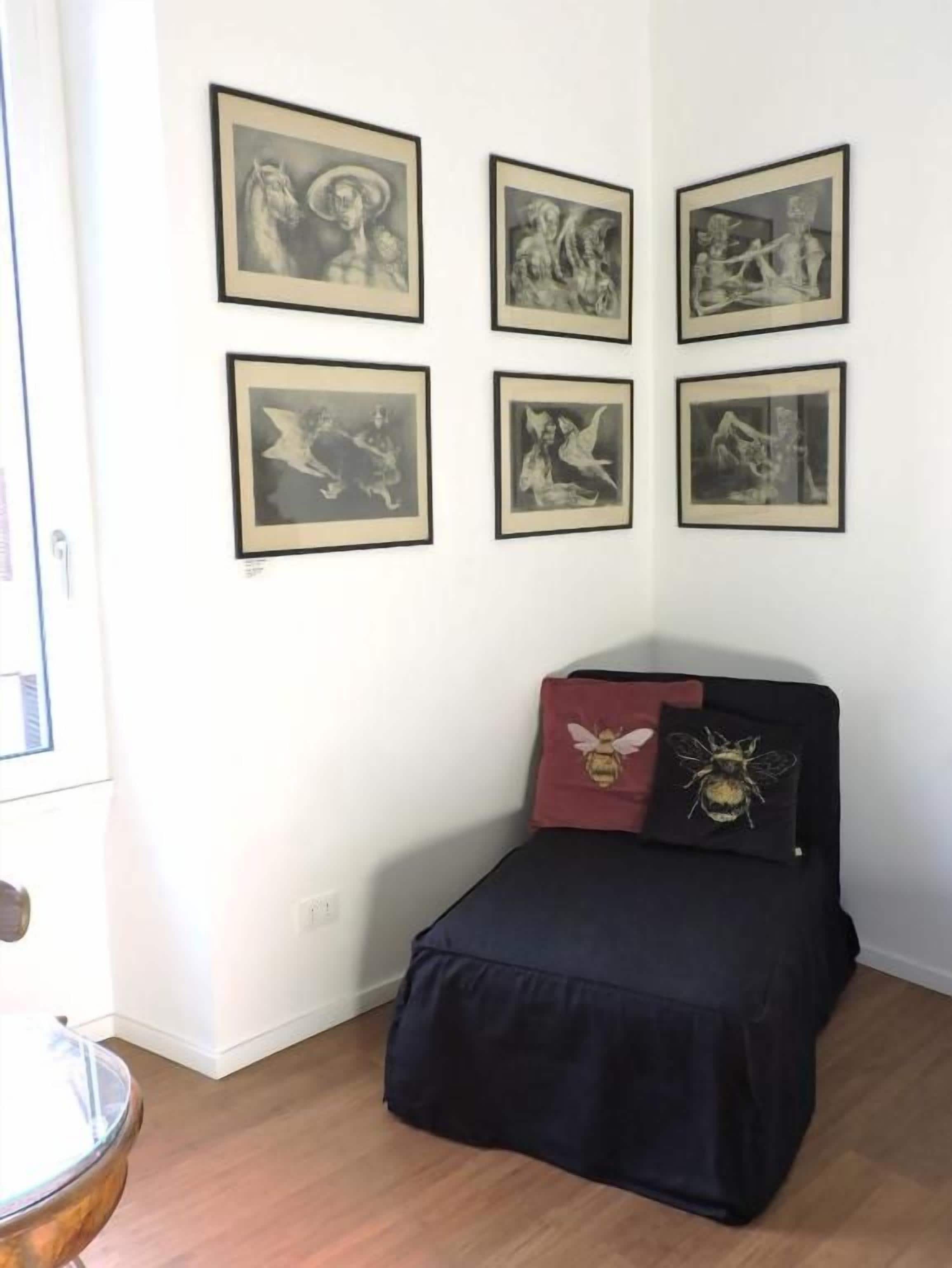 Una habitación con una cama, una pared con seis cuadros enmarcados y una puerta.