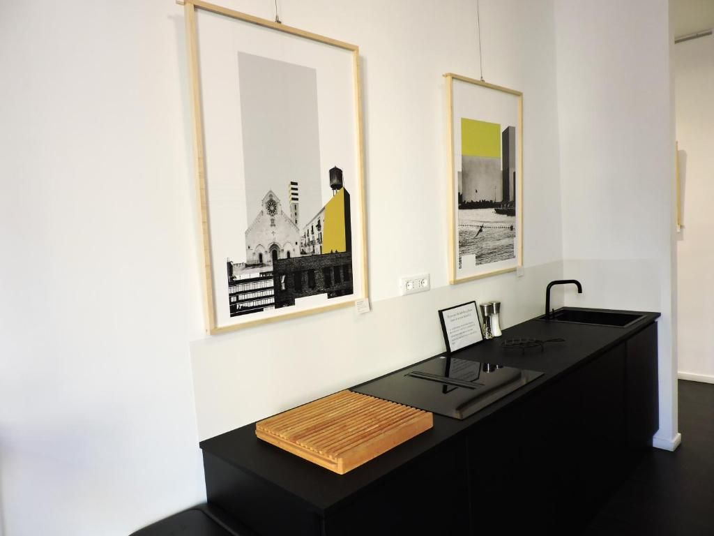 Un mostrador de recepción con obras de arte enmarcadas en la pared, una encimera negra y una bandeja de madera.