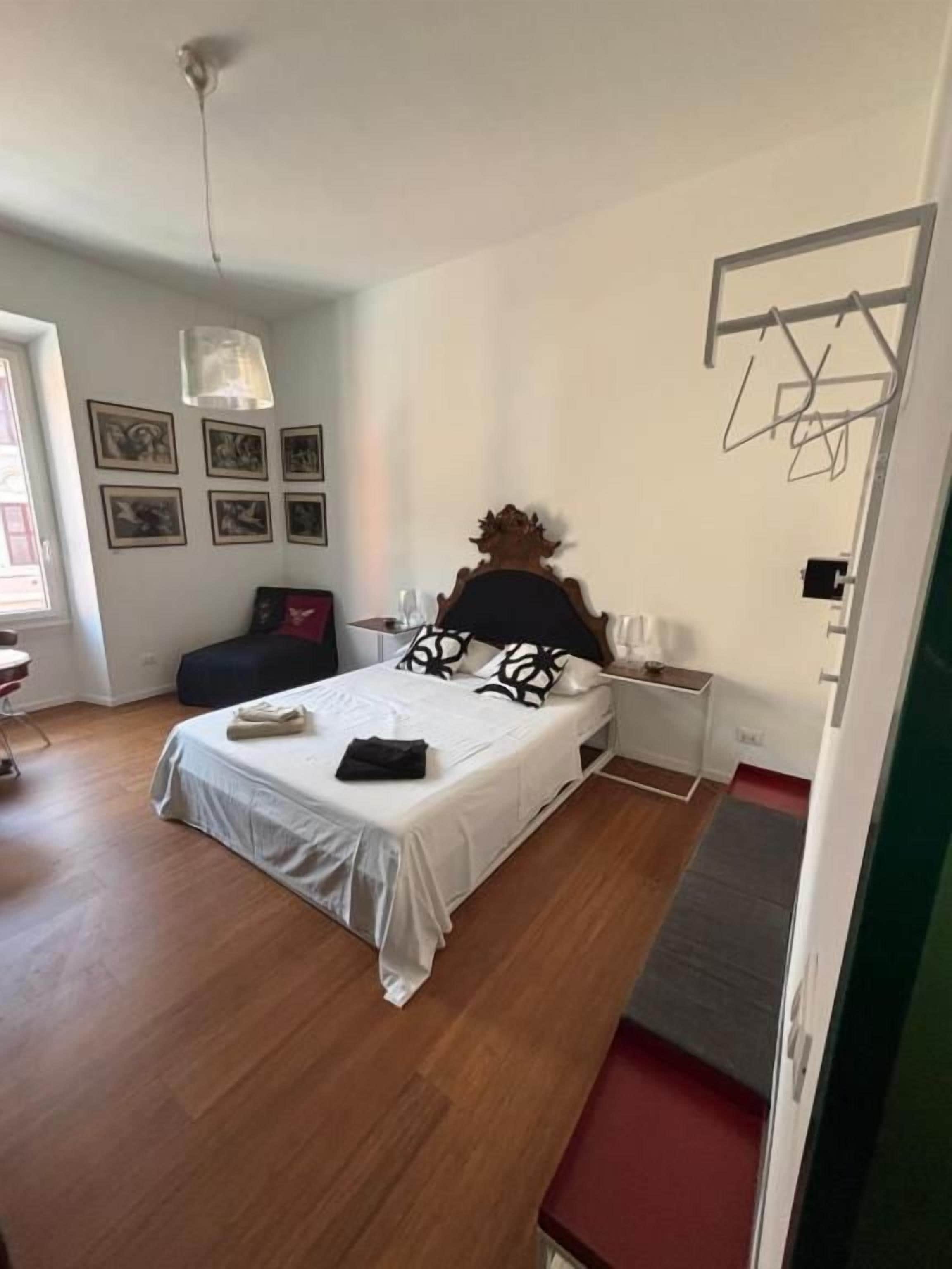 Un dormitorio con cama, mesitas de noche, lámpara colgante y un tendedero adosado a la pared.