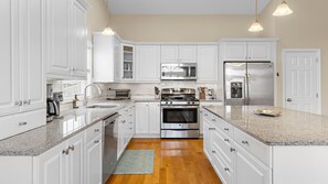 A modern kitchen with white cabinetry, stainless steel appliances, and granite countertops. - Beautiful 5 Bedroom Home with a pool in Holgate! (Beach Haven)