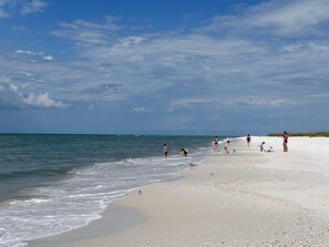 A beach with people walking and playing, a clear sky, and the ocean. -  NEW 4-bedroom house in Mexico Beach " SECOND WIND" (Mexico Beach)