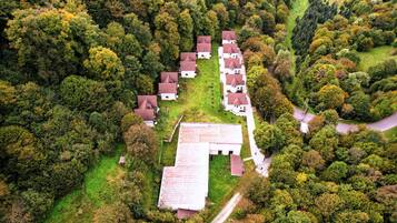 A cluster of houses with a central building, surrounded by dense forest.