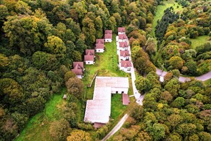 Un conjunto de casas con un edificio central, rodeado de bosque denso.