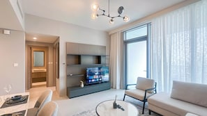 A modern living room with a sofa, a dining table set, a TV on a stand, and a large window with curtains. - Chic full Dubai Marina View 1 BR apartment in LIV Marina (Dubai)