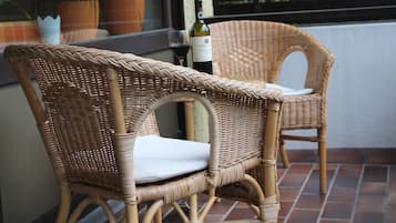 Dos sillas de mimbre con cojines en un patio empedrado.